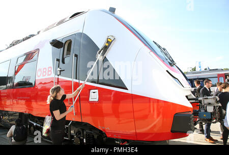 18 settembre 2018, Berlin: una fiera commerciale dipendente è la pulizia di un Bombardier treno delle ferrovie federali austriache a Innotrans fiera ferroviaria, mentre i visitatori a piedi attraverso la zona espositiva tra il sale sotto la torre della radio. Foto: Wolfgang Kumm/dpa Foto Stock