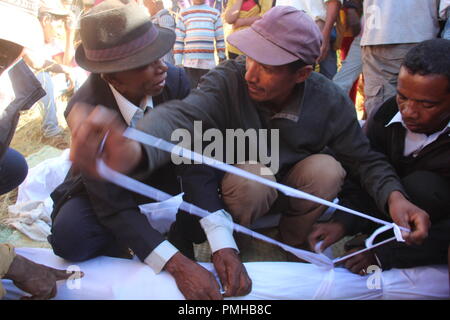 Masiniloharano, Madagascar. 25 Ago, 2018. Parenti si legano le spoglie mortali dei loro antenati in panni bianchi. Durante la fase 'Famadihana' (letteralmente: ruotando le ossa) cerimonia, persone in Madagascar il culto delle ossa dei loro antenati. Essi sono presi dalle loro tombe soprattutto per la grande festa. (A dpa 'Dance con i morti: Happy Corpse Festival in Madagascar' dal 19.09.2018) Credito: Jürgen Bätz/dpa/Alamy Live News Foto Stock