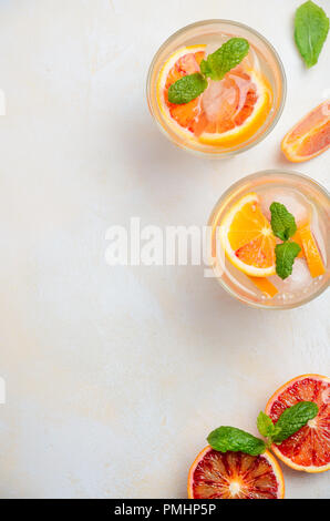 Cold drink rinfrescante con sangue fettine di arancia in un bicchiere su un cemento bianco sullo sfondo. Vista superiore, piana, laici copia spazio. Foto Stock