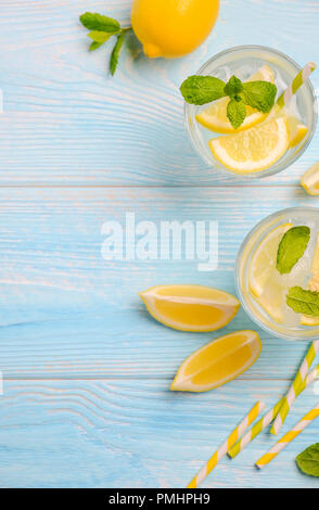 Il freddo estivo rinfrescante drink con limone e menta su luce blu sullo sfondo di legno, vista dall'alto, laici piana, copia dello spazio. Foto Stock