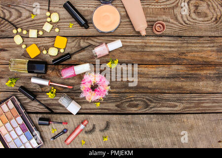 Cosmetici: mascara, perline, elastico fascia per capelli, ciglia finte, correttore, smalto per unghie, profumo, eyeliner, polvere, lucidalabbra, eye shadow e giallo flo Foto Stock