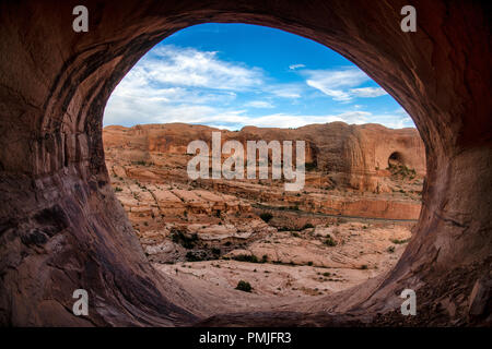 La vista guardando fuori di una grotta alta sopra il sentiero di arco di corona, Moab, Utah, Stati Uniti d'America Foto Stock