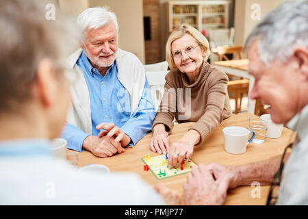 Coppia senior e amici divertirsi giocando gioco di bordo in casa di riposo o a casa Foto Stock