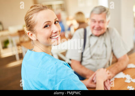 Happy nursing donna su un home visita comfort un uomo anziano Foto Stock