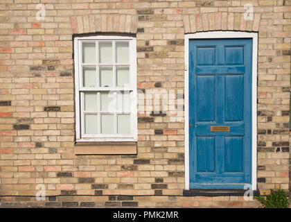 Blue vintage porta anteriore di un edificio restaurato del muro di mattoni di una casa Georgiana e la costruzione residenziale con il bianco in legno finestra a ghigliottina Foto Stock