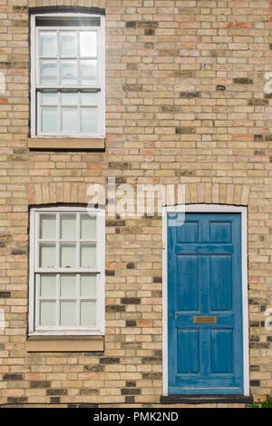 Pastello blu vintage porta anteriore di un edificio restaurato del muro di mattoni di una casa Georgiana e la costruzione residenziale con legno bianco finestre a ghigliottina. Foto Stock