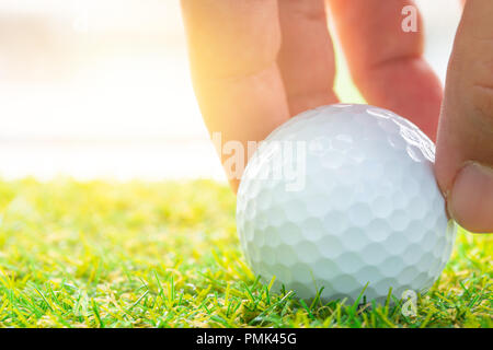 Posizionare a mano la pallina da golf sul campo da golf di colore verde per i business di avvio in buona posizione al concetto di successo Foto Stock