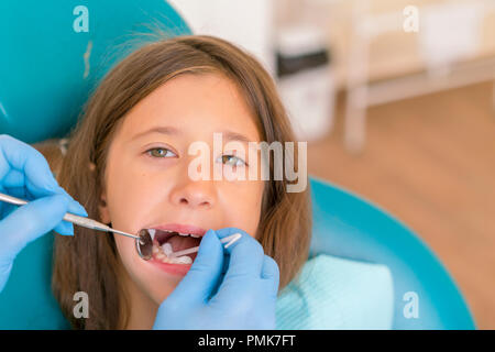 Immagine della bambina avente i suoi denti controllato dal medico. Bambina presso il dentista esaminando un perdere il dente con un dentista di specchio. Foto Stock