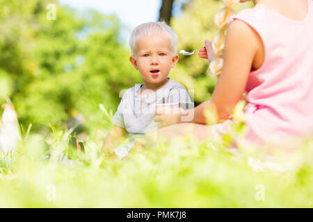 Alta-spirited piccolo bambino di mangiare nel parco Foto Stock