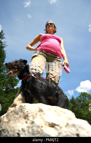 Incinta giovane donna su un estate a piedi con il suo cane nero. Foto Stock
