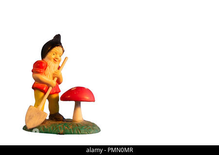 Close-up di annata in miniatura il giardinaggio gnome con una piccola pala e rosso toadstool veleno, fungo isolato su sfondo bianco Foto Stock
