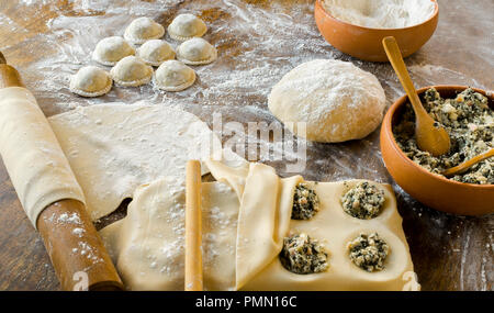 Rendendo la pasta fatta in casa: la pasta preparata e impastati, ripiene di ricotta, bietole e prosciutto, grandi ravioli rotondo (Sorrentino) preparata e leggere Foto Stock