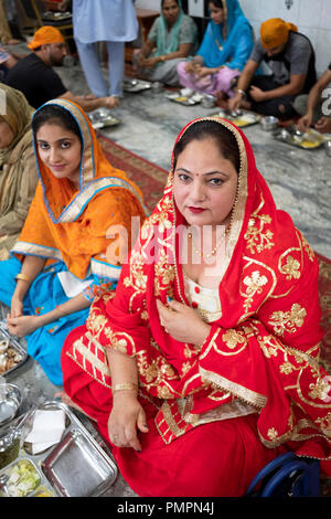 Una donna e suo nipote a mangiare in un tempio sikh langar una sala dove gli ospiti sono serviti cibo vegetariano. Foto Stock