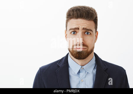 Chi può respingere questo cutie con gli occhi blu. Affascinante e bello ragazzo carismatico con la barba e malati delle sopracciglia accigliata rendendo sciocco e viso carino busbana francese chiedendo per favore o scusandosi Foto Stock