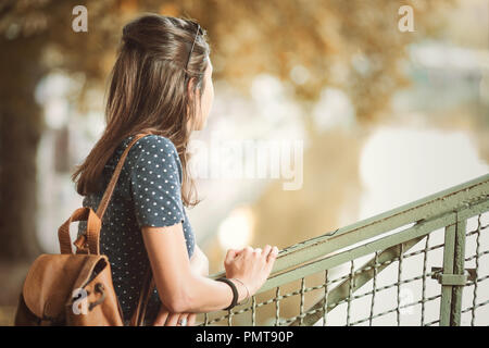 Giovane donna appoggiata su un corrimano in autunno Foto Stock