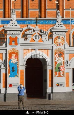 Riga di punti neri House, vista posteriore di un turista di scattare una foto dell'ingresso alla Casa delle Teste Nere in Ratslaukums piazza nel centro storico di Riga, Lettonia. Foto Stock