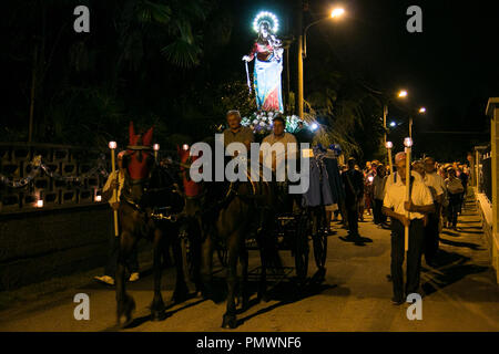 Una statua della Vergine Maria viene trasportato su un cavallo e pullman attraverso le strade durante una notte tempo processione in Arconate, Italia settentrionale. Foto Stock