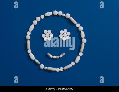 Pills formando faccina sorridente su sfondo blu Foto Stock