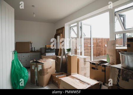 La sala da pranzo è piena di mobili e scatole di cartone come una famiglia in movimento. Foto Stock