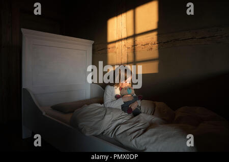 Ragazza abbracciando Teddy bear a letto Foto Stock