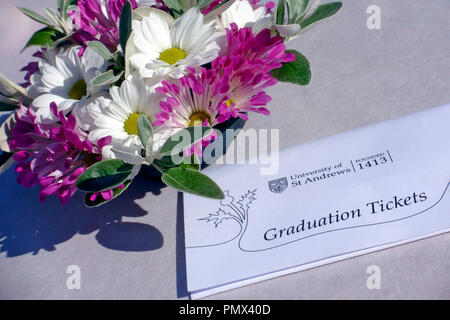 Università di St Andrew's graduazione di biglietti su un tavolo accanto a una decorazione floreale Foto Stock