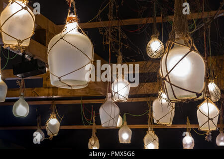 Molto insolito lampade vintage fatta di bottiglie di vetro in corda che pende dal soffitto del ristorante. Foto Stock