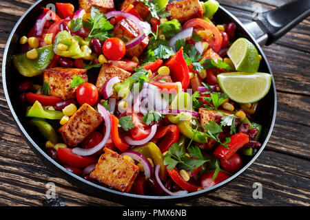 Verdure miste Saute veloce e salutare antipasto consistono di pomodori maturi, peperoni dolci di mais, fagioli neri, tofu, guarnite con prezzemolo, spruzzata w Foto Stock