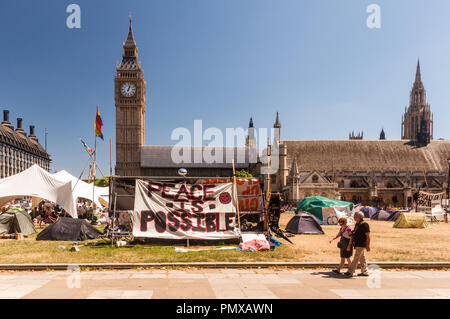 London, England, Regno Unito - 4 Luglio 2010: pedoni a piedi passato la democrazia protesta Villaggio camp che occupa la piazza del Parlamento, al di fuori delle case di Parlia Foto Stock