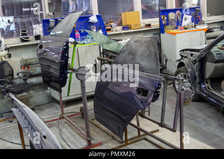 Due auto blu parti della porta sono installati su rack dopo la verniciatura in auto repair shop in camera con gli strumenti e le attrezzature per la riparazione di parti del corpo Foto Stock
