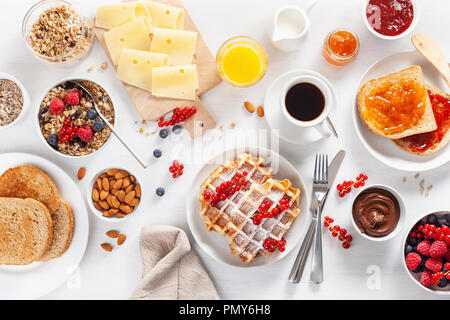 La prima colazione con muesli dadi berry, waffle, toast, marmellata, cioccolata spalmabile e caffè. Vista superiore Foto Stock