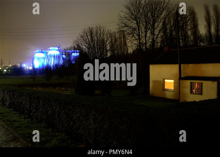 Illuminato blu del camino di un impianto di depurazione delle acque reflue di la Emschergenossenschaft di Bottrop tower misteriosamente oltre i dintorni. Un impianto di depurazione delle acque reflue è uno dei più grandi in Europa e pulisce l acqua inquinata di Emscher. Foto Stock