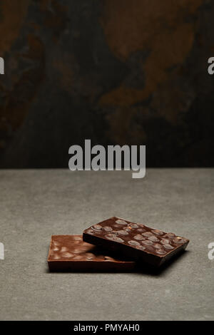 Deliziosa barrette di cioccolato con dadi su sfondo grigio Foto Stock