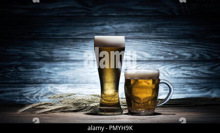 Due bicchieri di birra dorata e frumento spikelets sul tavolo di legno, oktoberfest concept Foto Stock