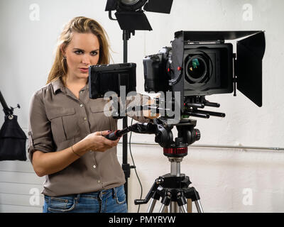 Foto di una donna operando una fotocamera DSLR rig per riprese video. Foto Stock