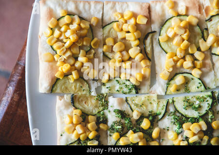 Cibo sano, pizze o focacce w/ il mais dolce e zucchine. Retroilluminazione, sano e vegano vegetariano. Fotografia di cibo. Tabella, le erbe aromatiche e i broccoli. Foto Stock