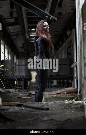 Ritratto di giovane donna con grounge lunghi capelli rossi che pongono in una casa abbandonata piena di graffity Foto Stock
