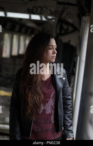 Ritratto di giovane donna con grounge lunghi capelli rossi che pongono in una casa abbandonata piena di graffity Foto Stock