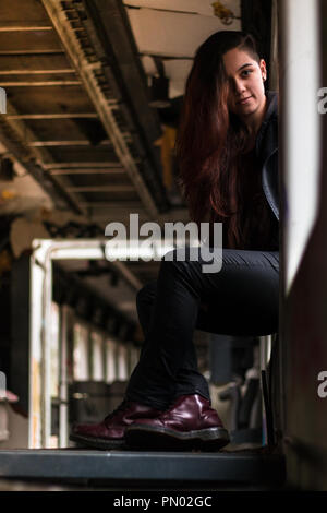 Ritratto di giovane donna con grounge lunghi capelli rossi in posa di un abbandonato il vecchio treno finestra Foto Stock