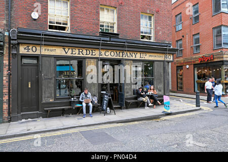 Le persone al di fuori seduta Verde & Company bere il tè e mangiare a un tavolo in estate in Spitalfields Est Londra Inghilterra E1 UK KATHY DEWITT Foto Stock