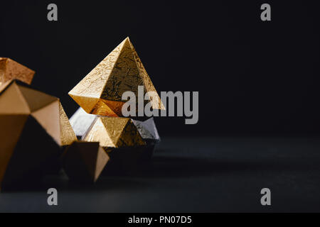 Cose-vista del lucido scintillante sfaccettato pezzi in oro su sfondo nero Foto Stock