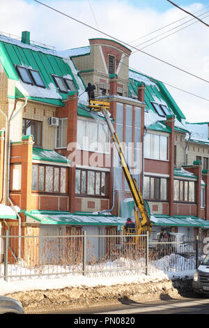 Il servizio di pulizia pulisce la neve dal tetto della casa. Foto Stock