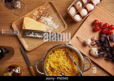 Vista dall'alto di spaghetti in metallo scolapasta circondato con vari ingredienti per la pasta sul tavolo di legno Foto Stock