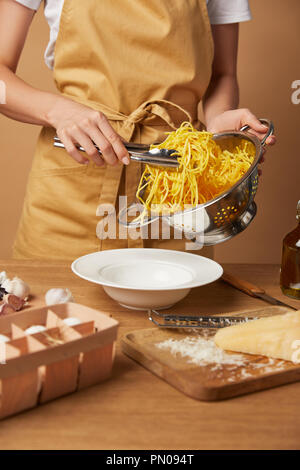 Ritagliato colpo di donna mettendo gli spaghetti sulla piastra con