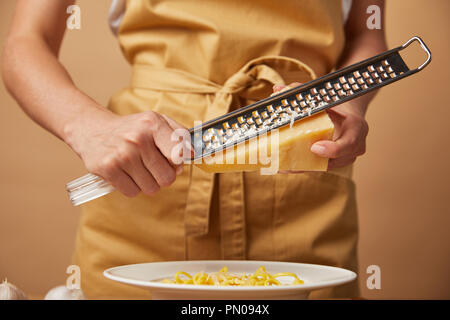 Ritagliato colpo di donna grattugiare il formaggio su spaghetti Foto Stock