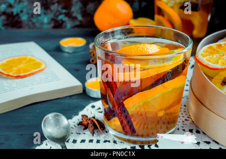 Due vetri con riscaldamento aromatico arancione speziato tè, varietty frutta secca chips e frutta rotoli di pelle nella casella sul tavolo scuro. Copia dello spazio. Foto Stock