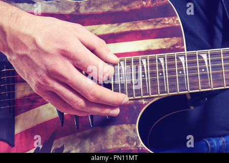 L'uomo in una camicia nera e jeans riproduce una chitarra acustica. Dita dettaglio Foto Stock