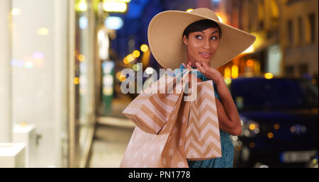 Giovani razza mista femmina pone shopper tenendo le borse della spesa al di fuori Foto Stock