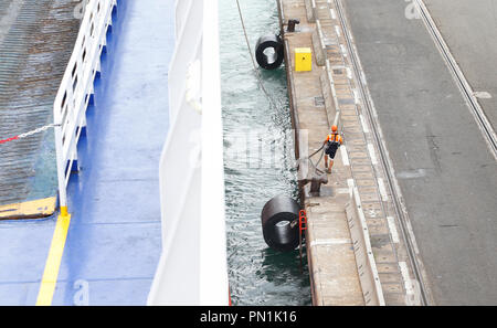 Scaricatore di porto o impresa di movimentazione cammina accanto a una appena arrivati nave nel porto di Barcellona. Foto Stock