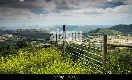 Un recinto si trova sulla cima di qualche erba con un paesaggio collinare in background. Foto Stock