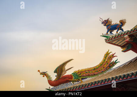 Bella dragone cinese capo-unicorn e cinese phoenix statue sul tetto nel tempio cinese con drammatico sfondo del cielo. Foto Stock